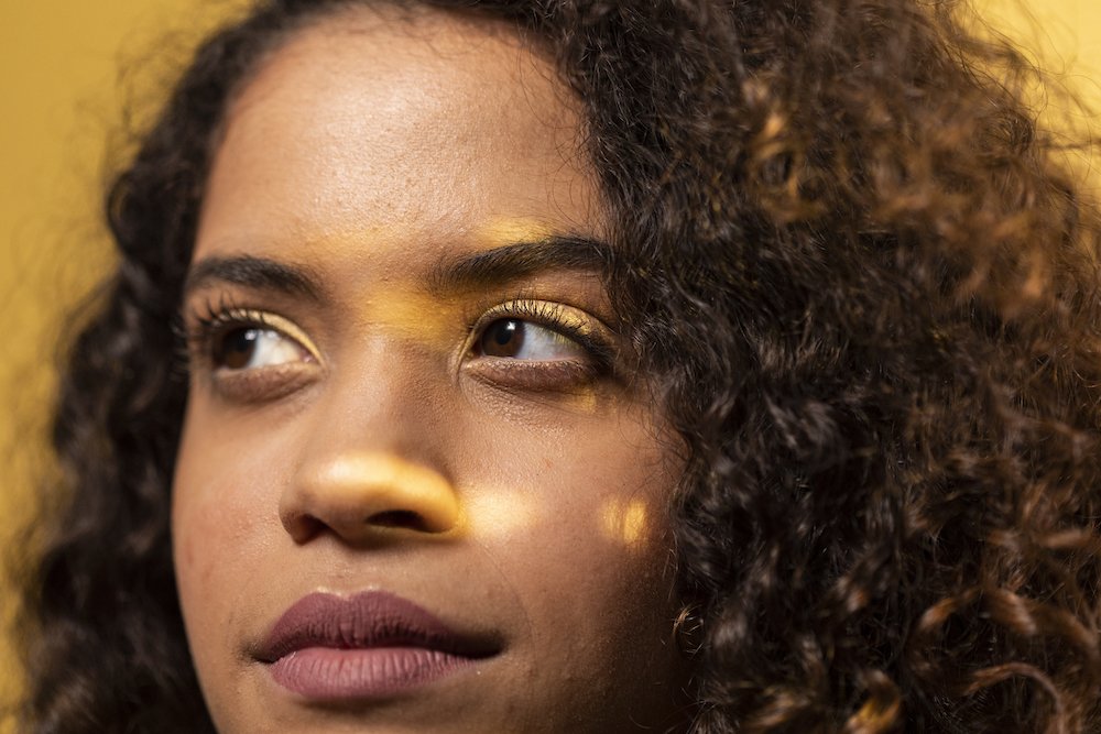 a close up shot of a girl with yellow light on her face