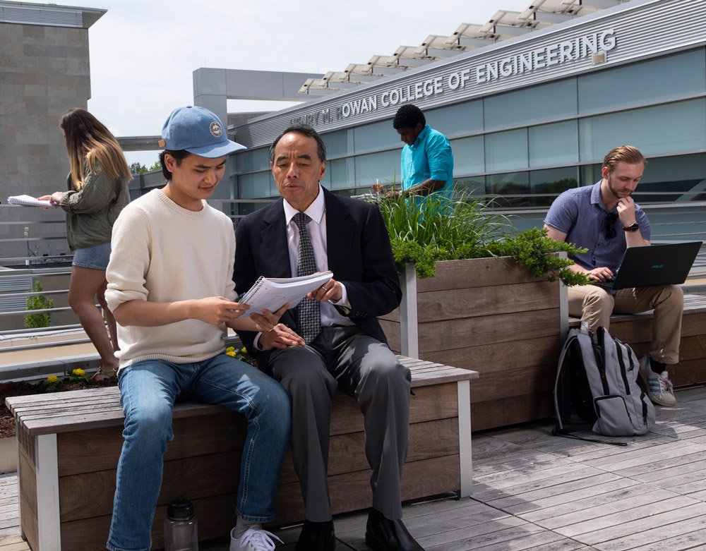 Assistant Dean of Engineering sits with student to study on engineering building terrace