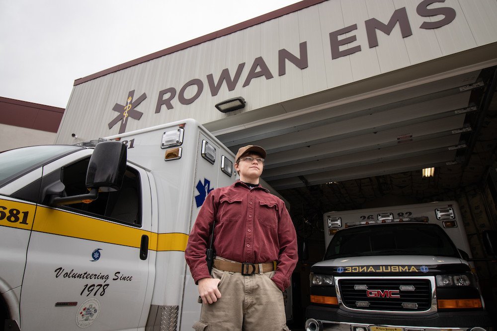 A student standing in front of the EMS ambulances
