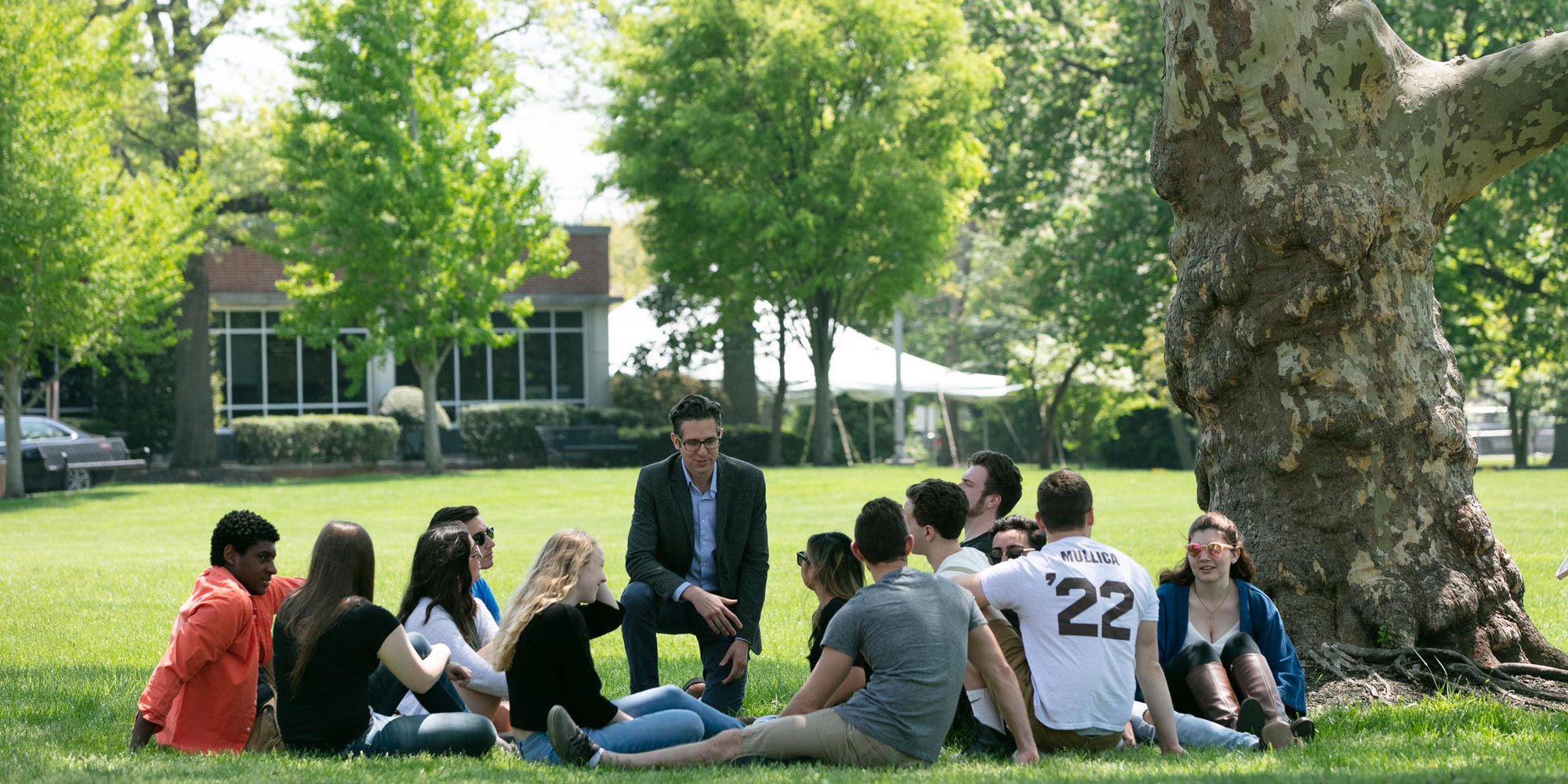 Rowan University students sit outside listening to a history professor.