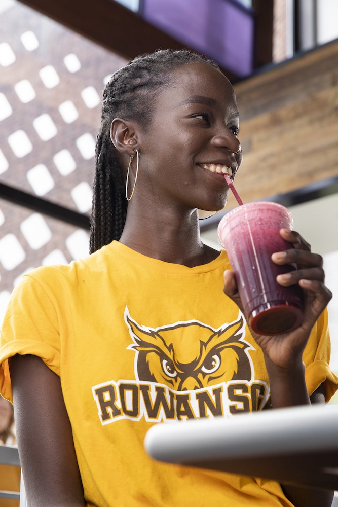 A close up portrait of a student drinking a smoothie.