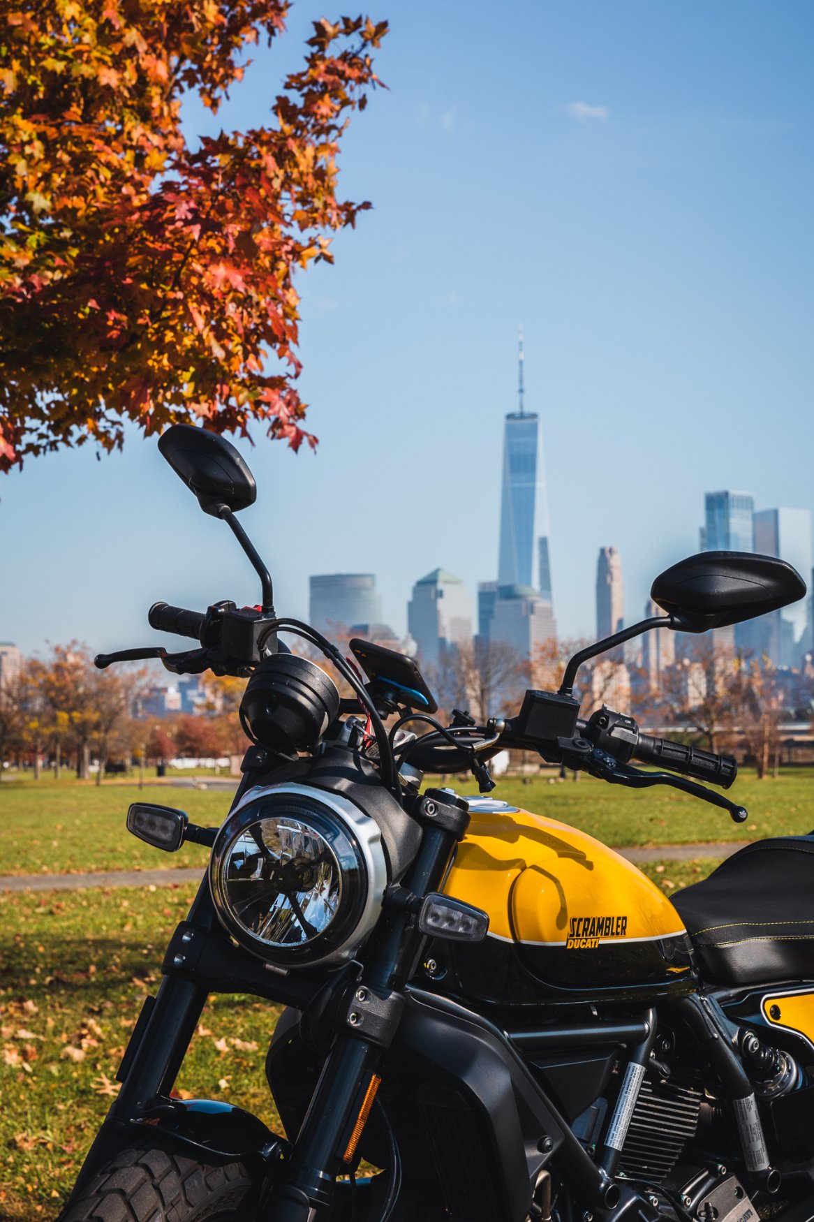 Yellow motorcycle with New York City skyline behind it. 