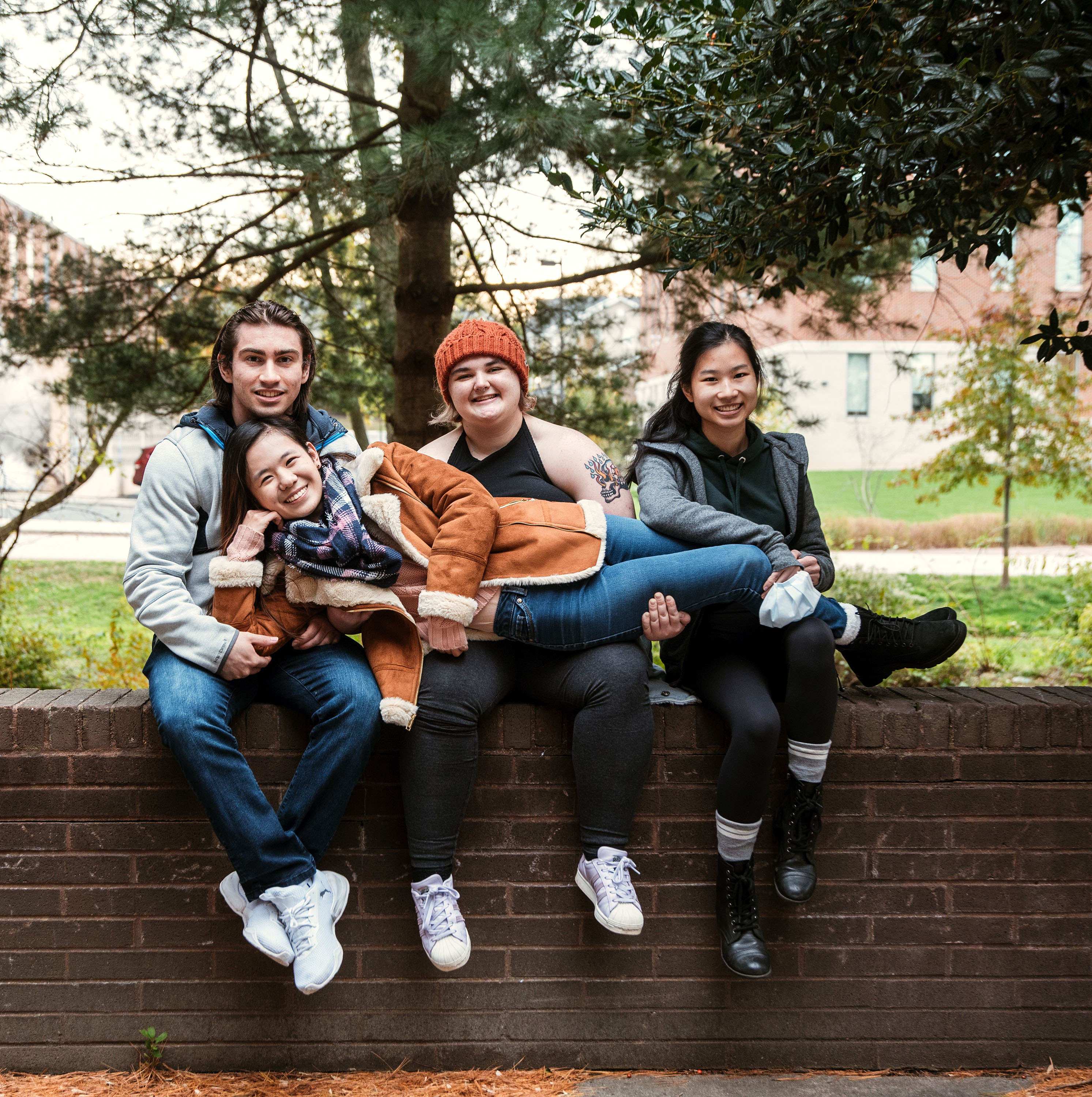 Three students sitting and and holding another student sideways in the air.