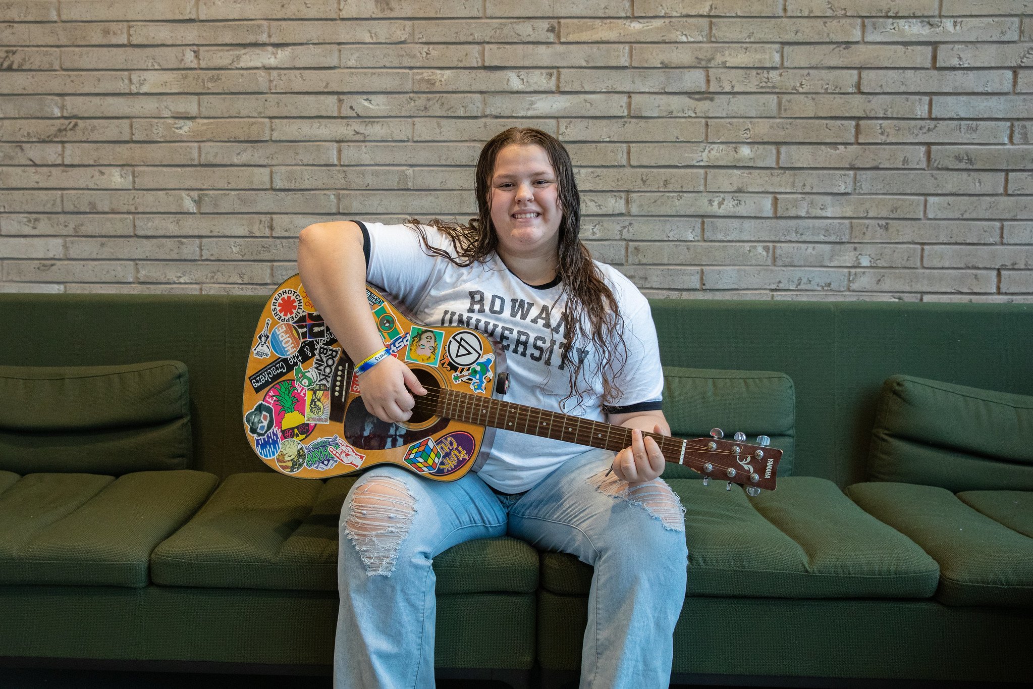 Rowan University student Laynie poses for the camera while holding a guitar. 