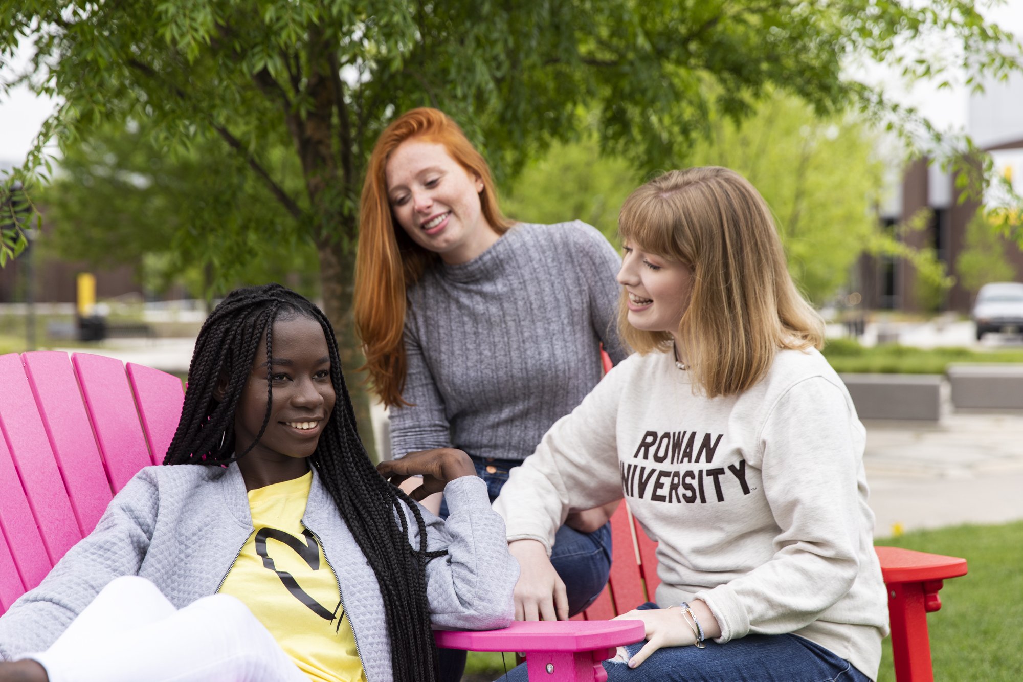 Three Rowan University female students sitting outside on a sunny day.