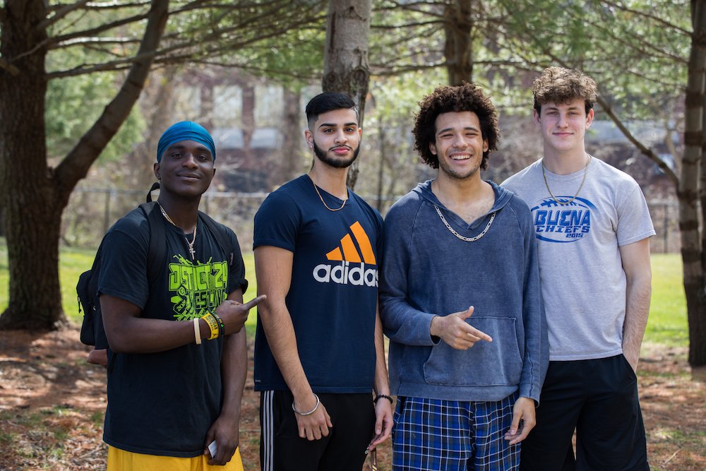 Four male students stand shoulder to shoulder, smiling.