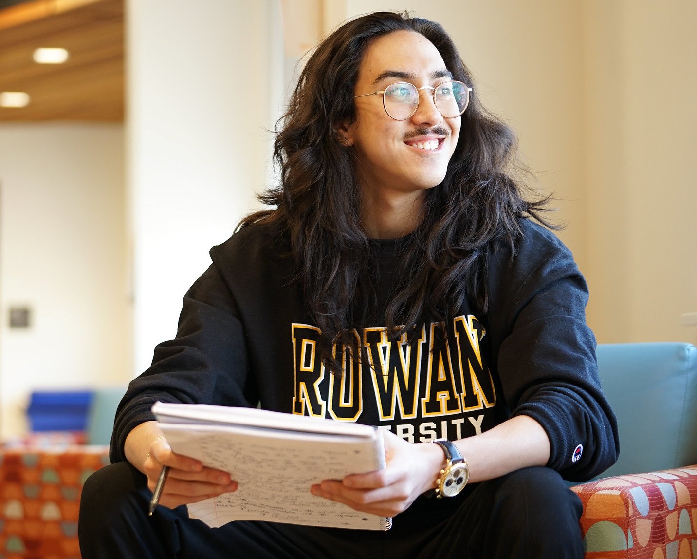 A student in a Rowan shirt holding a notebook.