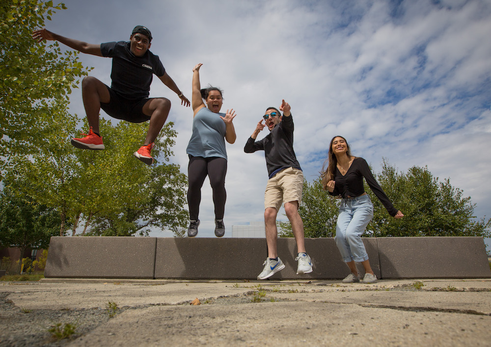 Four students with big smiles jumping in the air.