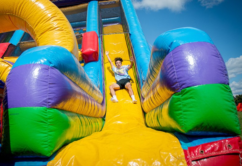 Rowan University student slides down an inflatable slide at an event.