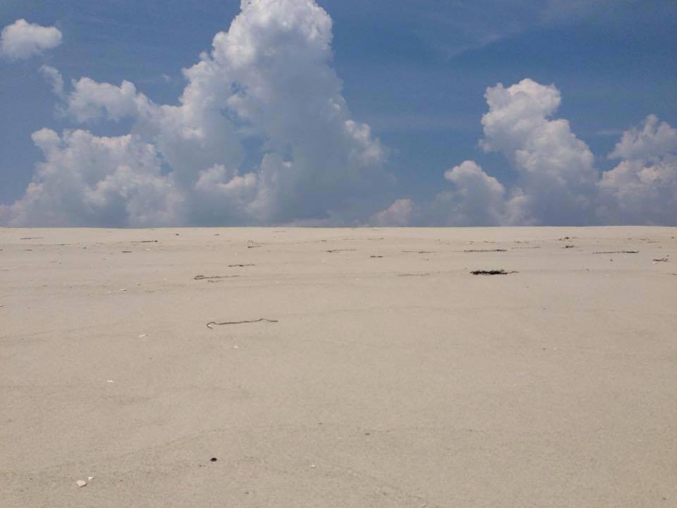 Close up of sand with clouds behind.