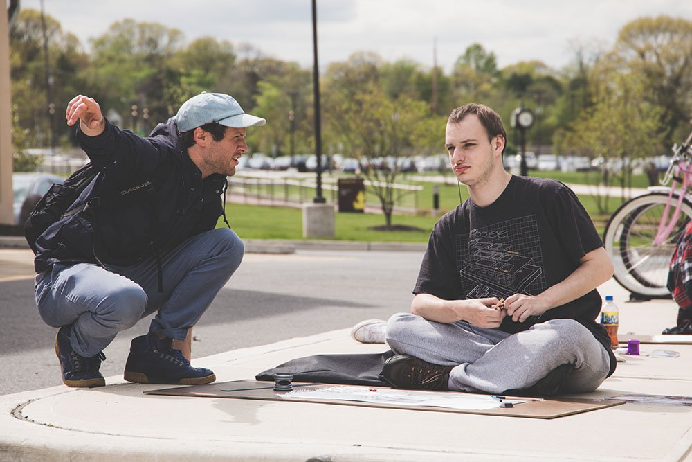 A professor and a student working outside on a drawing