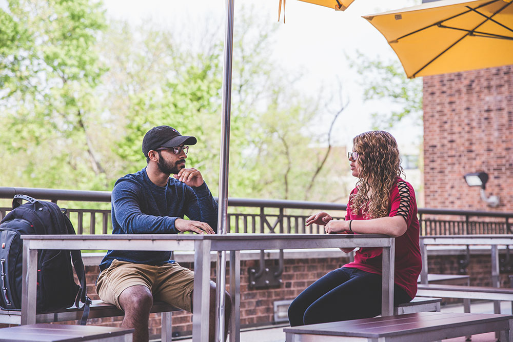 two students sitting out at a picnic table.