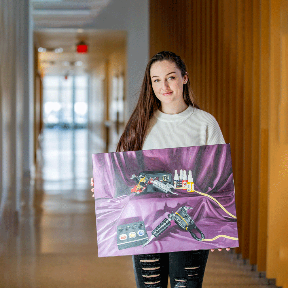 Megan holds one of her art pieces inside an academic building on campus.