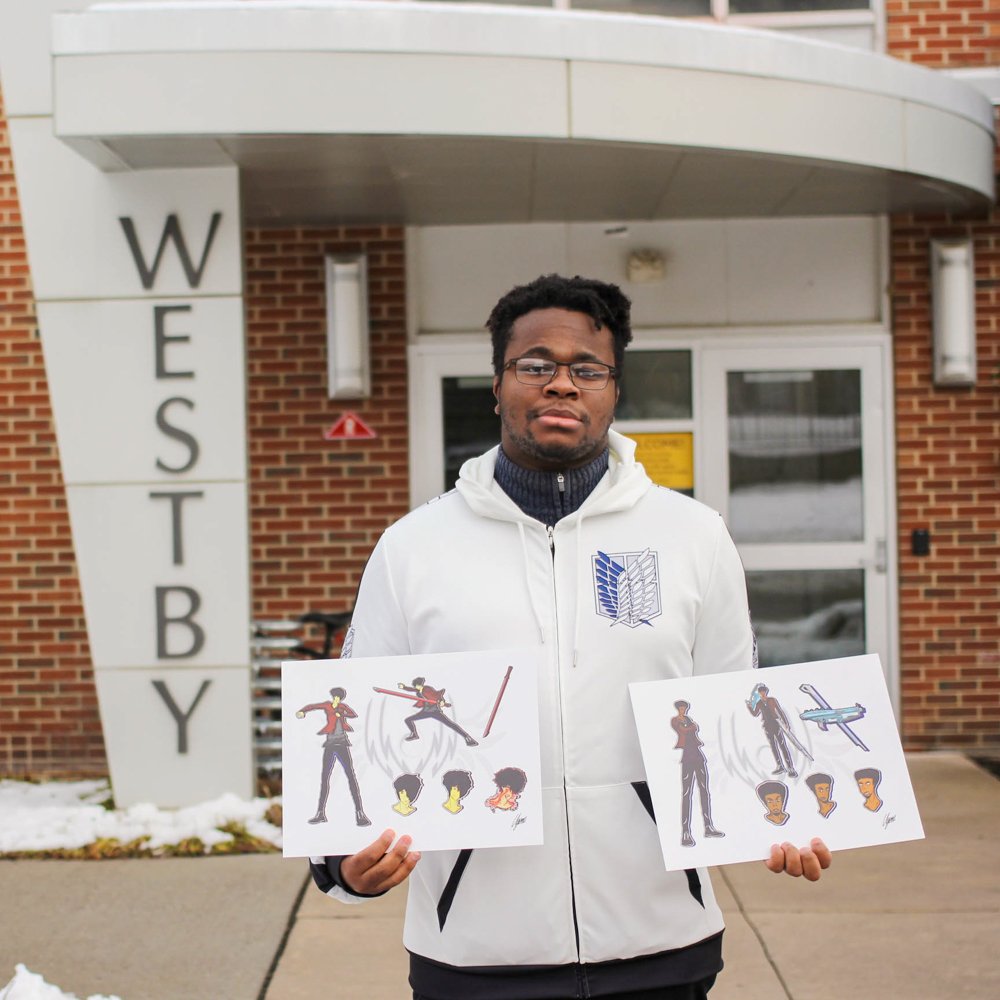 Ugonna holding two pieces of his art in front of Westby.