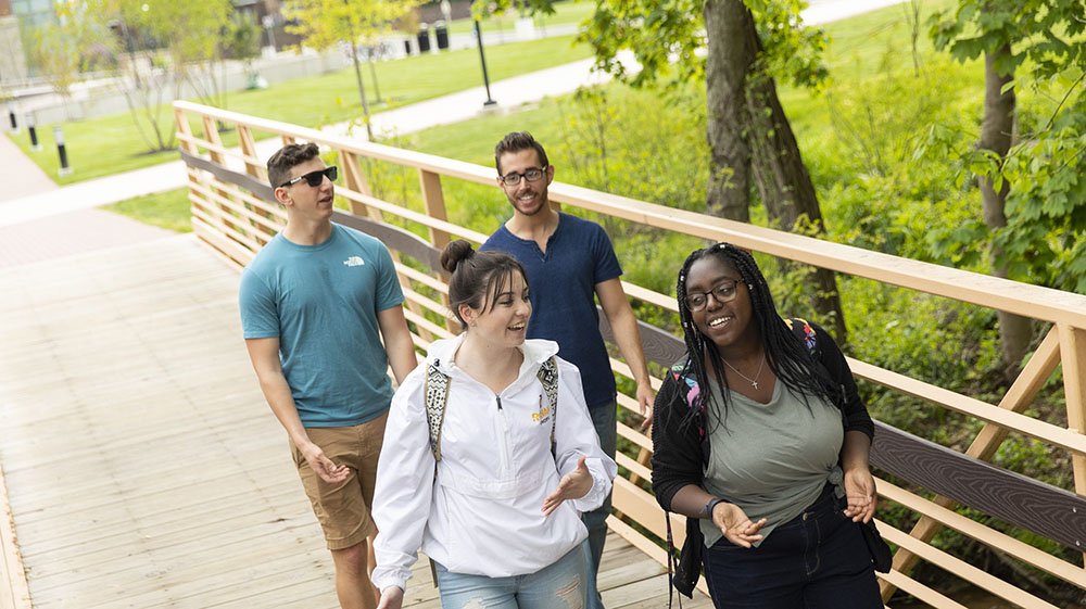 students walking across a bridge on campus.