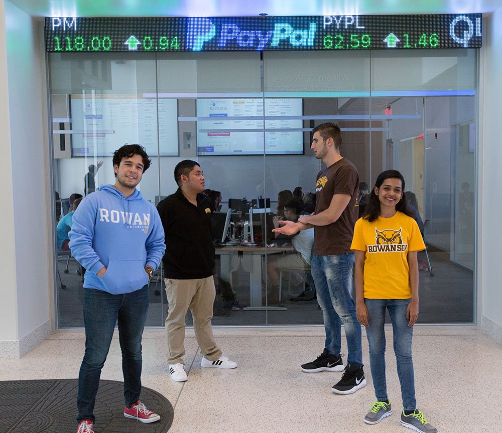 College students standing in a trading room.