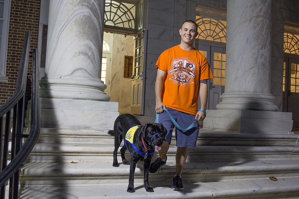 Jimmy on steps of Bunce Hall with service dog.
