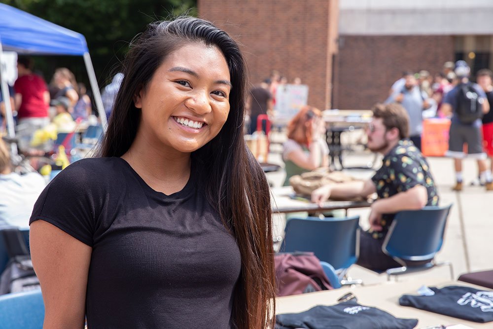 girl smiling on campus in outdoor seating area