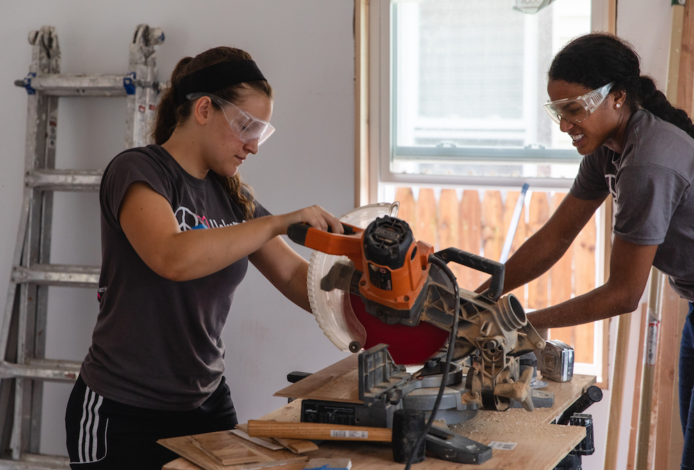 Two students work together with a saw.