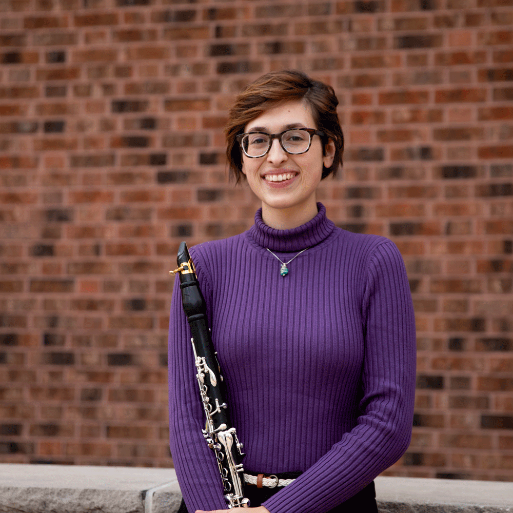 Emily smiles broadly while holding a clarinet.