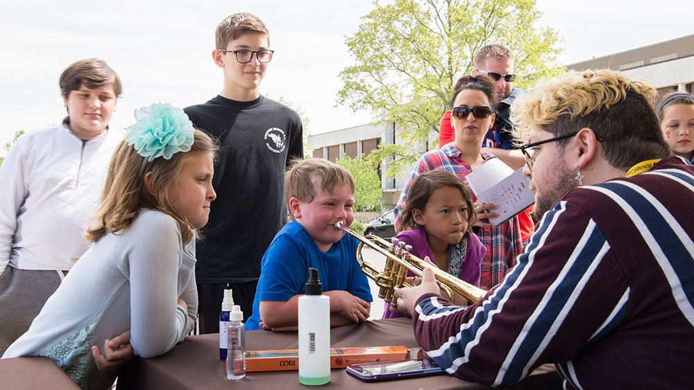 Music education major shows students various instruments.