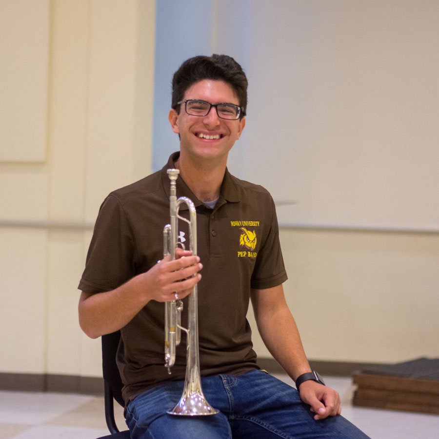 Music education major Michael sitting with a trumpet.