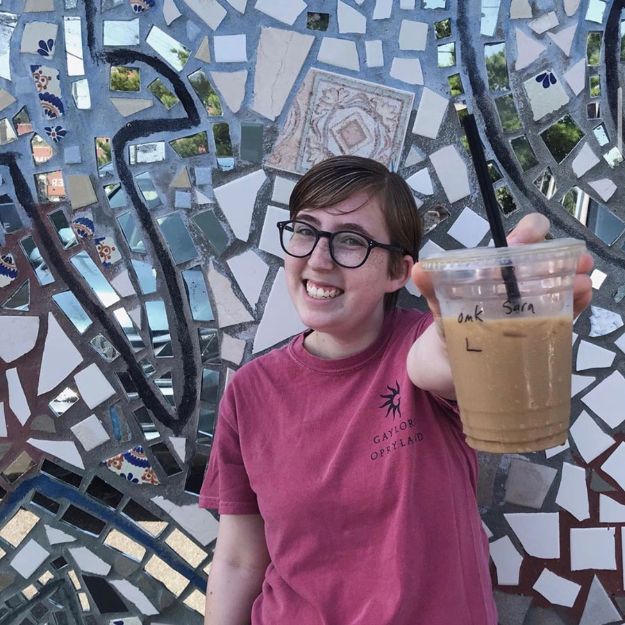 Gavin holding a beverage in front of a mosaic tile wall