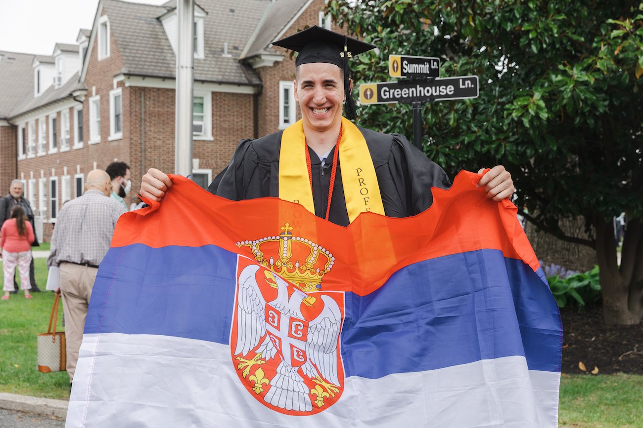 Marko stands holding a flag from Serbia.