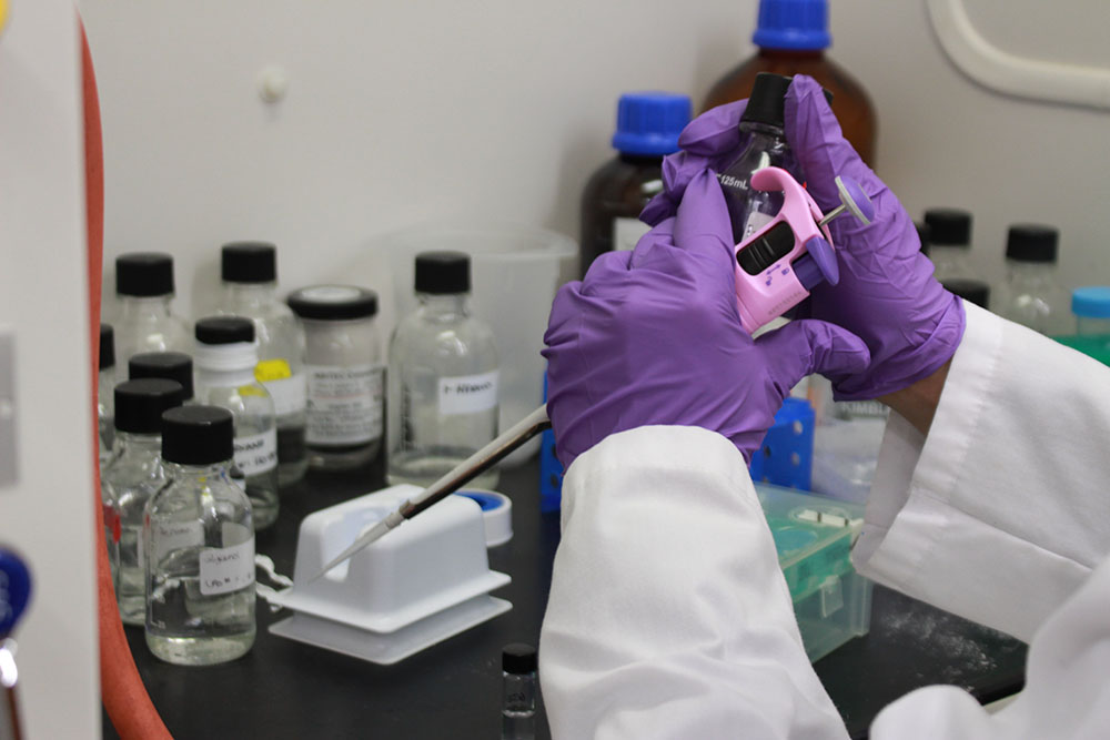 gloved hands doing work with test tubes
