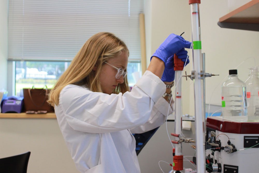A female student working in a science lab, with a pipette in her hand.