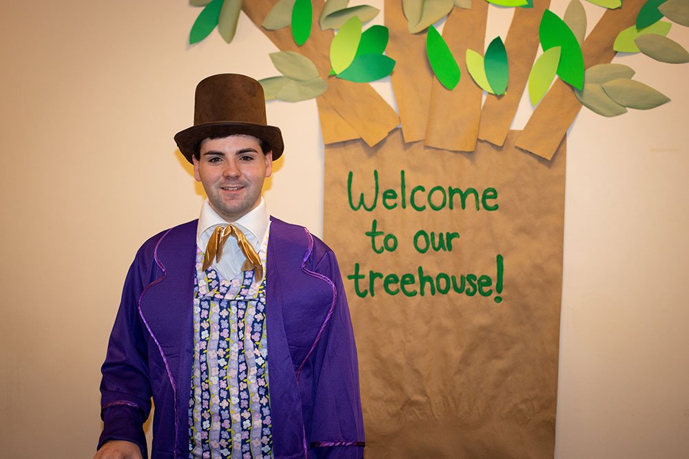 Sean L. dressed up in front of a treehouse sign