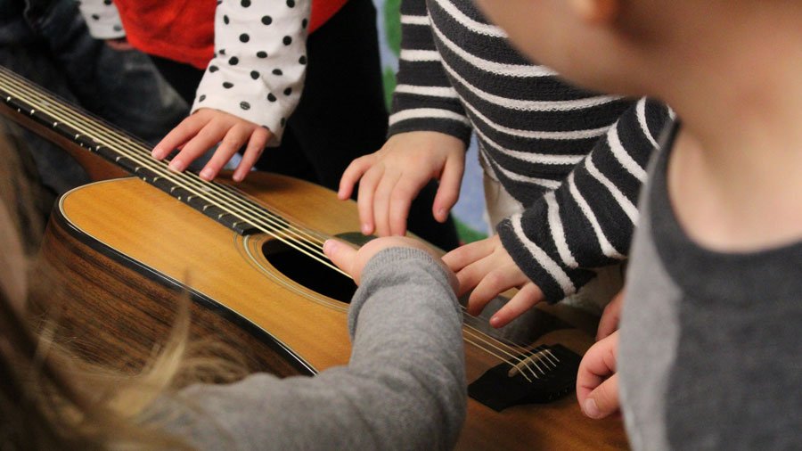 Elementary students playing on a guitar