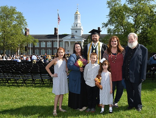 Jeremaih poses in graduation attire with his family.