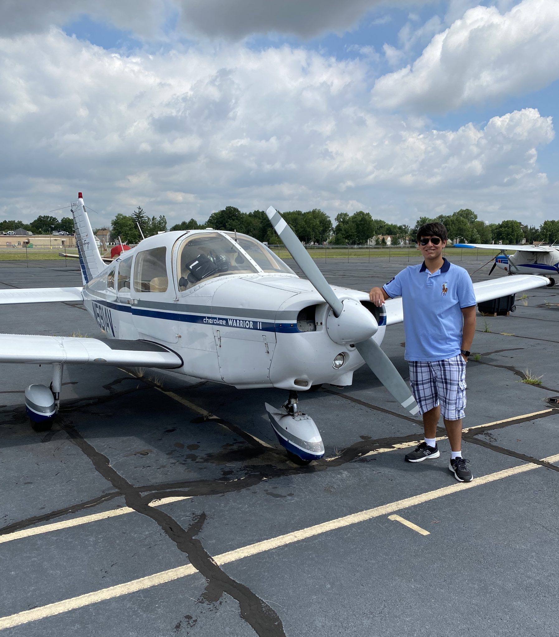 Jay poses in front of a airplane.