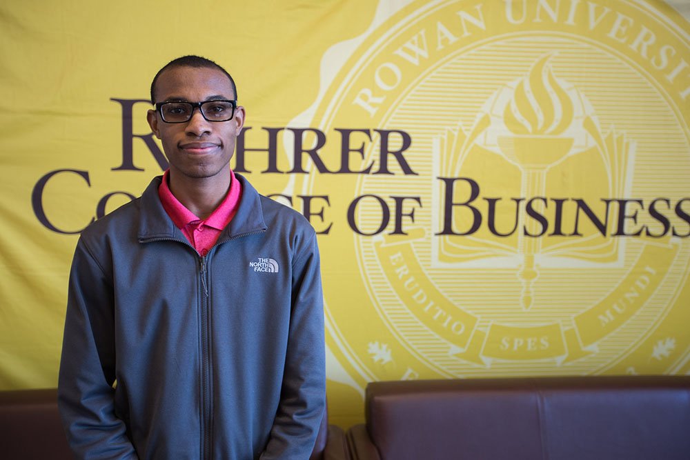 Davon D. standing in front of a Rohrer College of Business banner