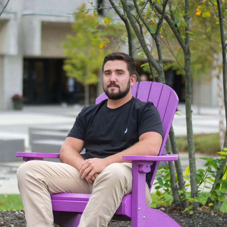 Nicholas C. sitting in a purple Adirondack chair