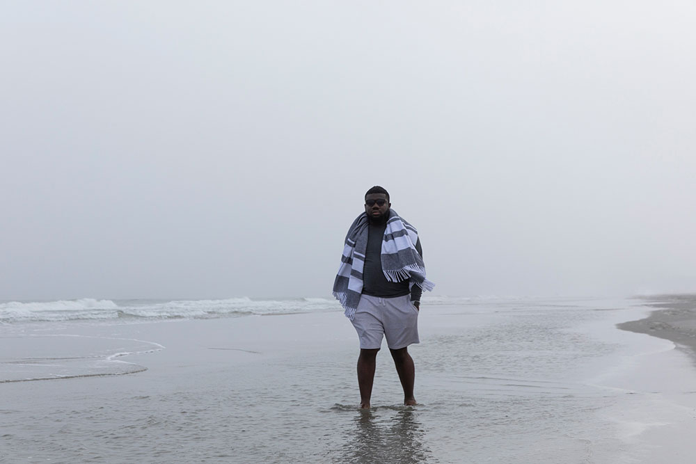 college student standing on the beach with a blanket