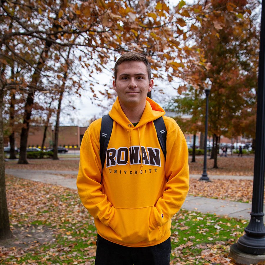 Joshua standing on campus in a Rowan hoodie