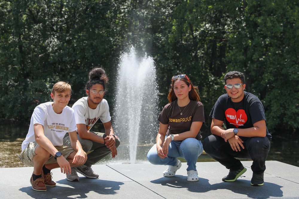 A group of four pre-college institute students outside engineering pond
