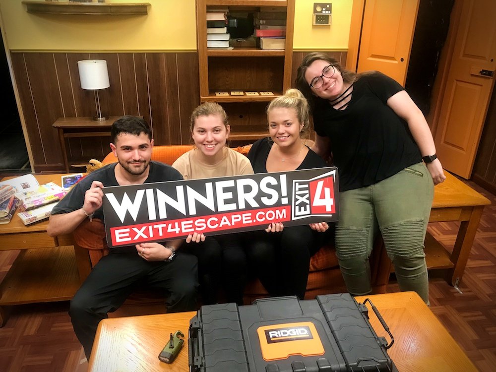 group of students pose together with a winner sign from an escape room