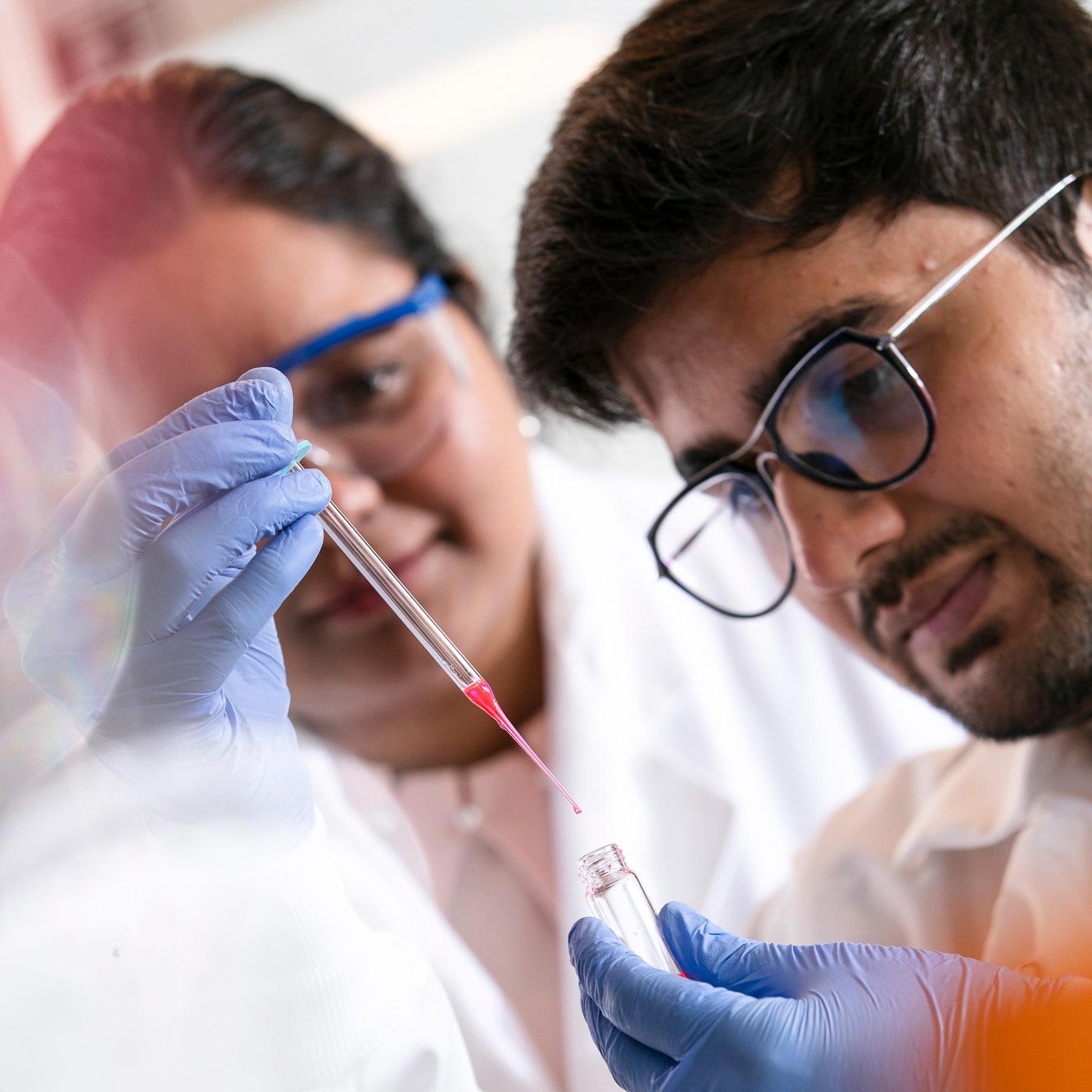 student in lab looking at a test tube