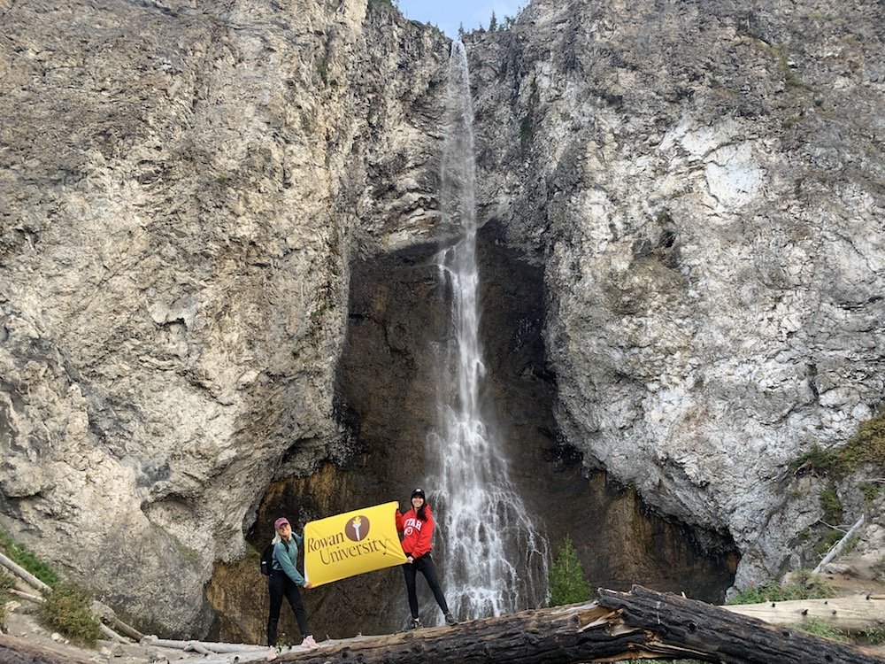 Two students holding a rowan university flag in yellowstone