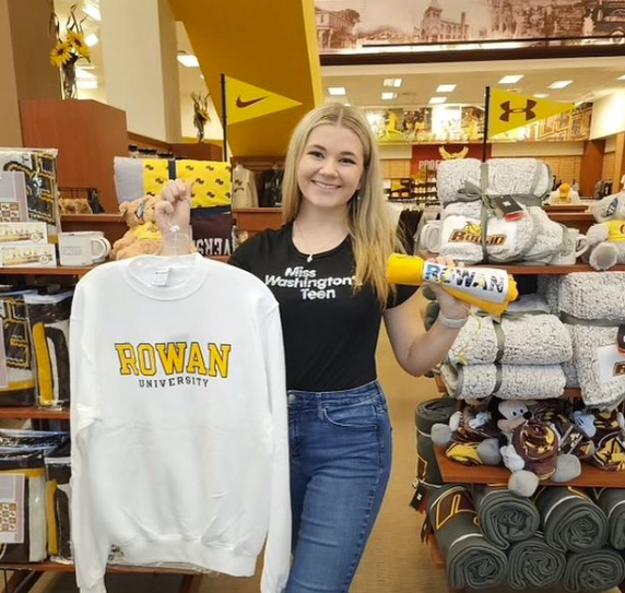 A student holding Rowan apparel at the bookstore.