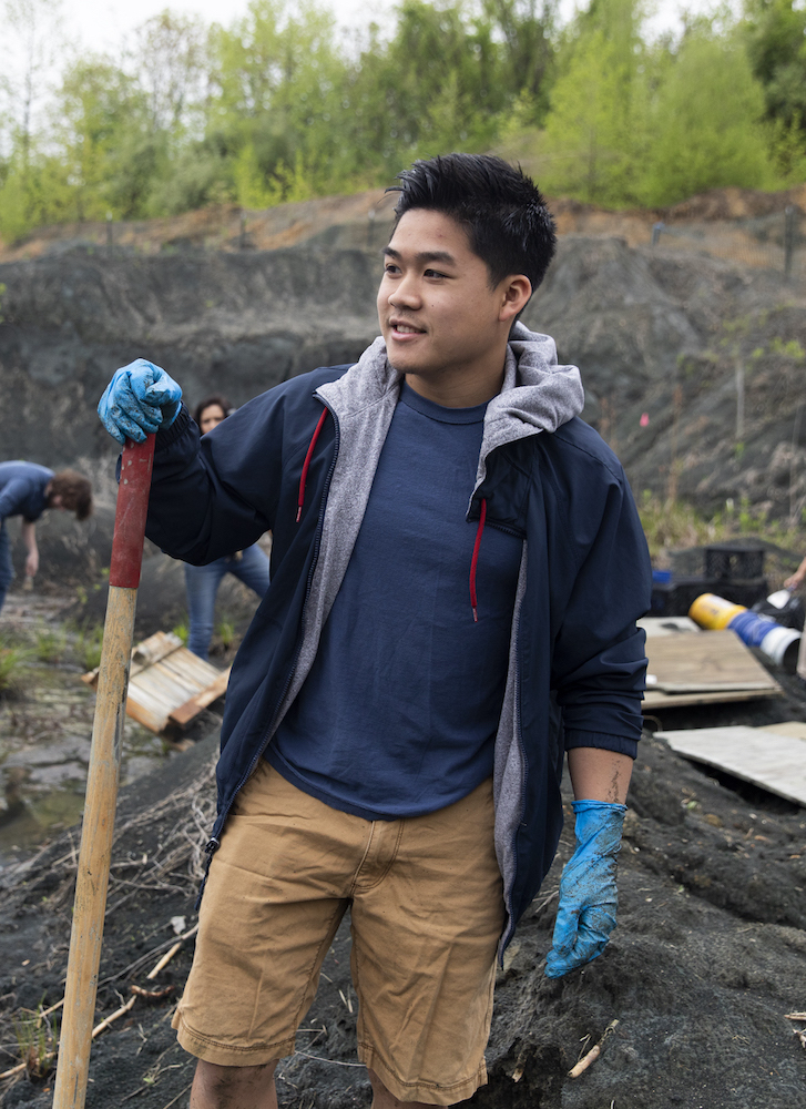 A boy standing in the fossil park with a shovel.