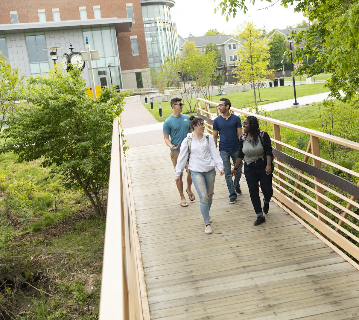 Four students walking over a bridge.