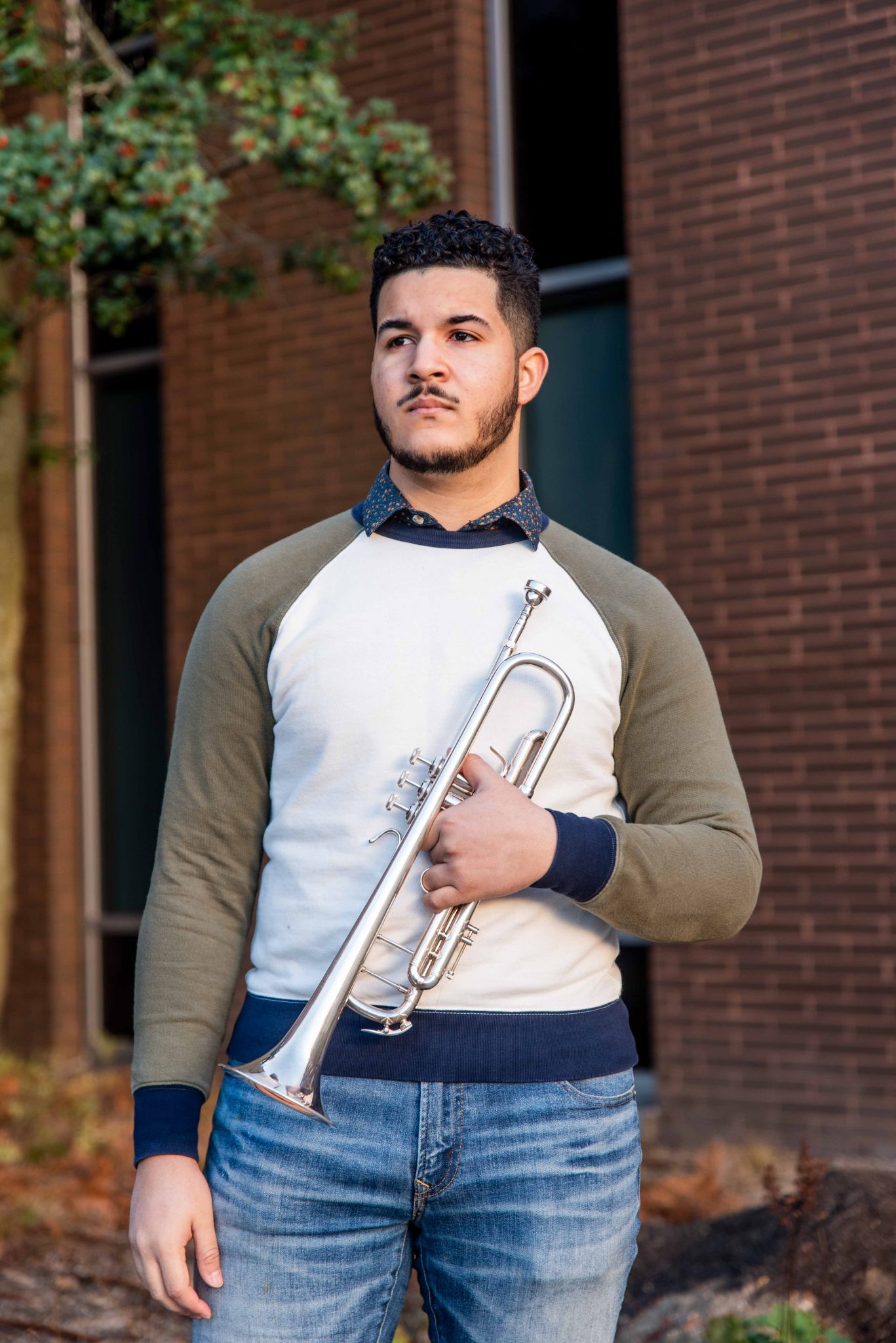 Luis holding a trumpet outside Wilson Hall.