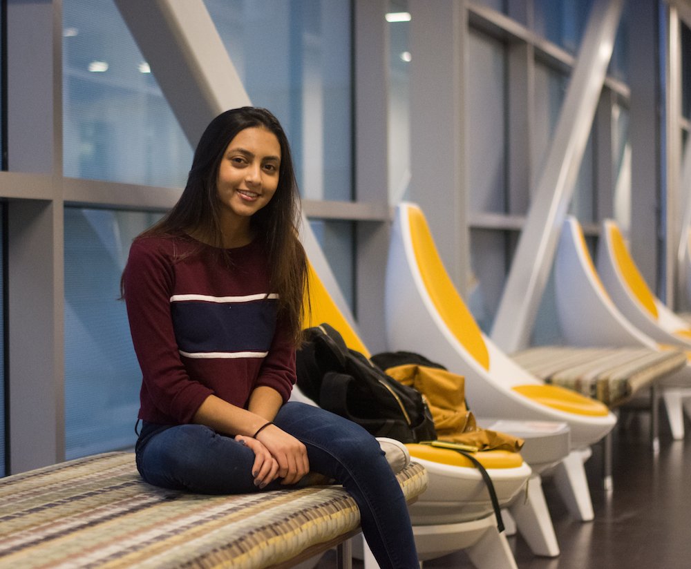 Maya sits in a chair along a row of chairs in engineering hall