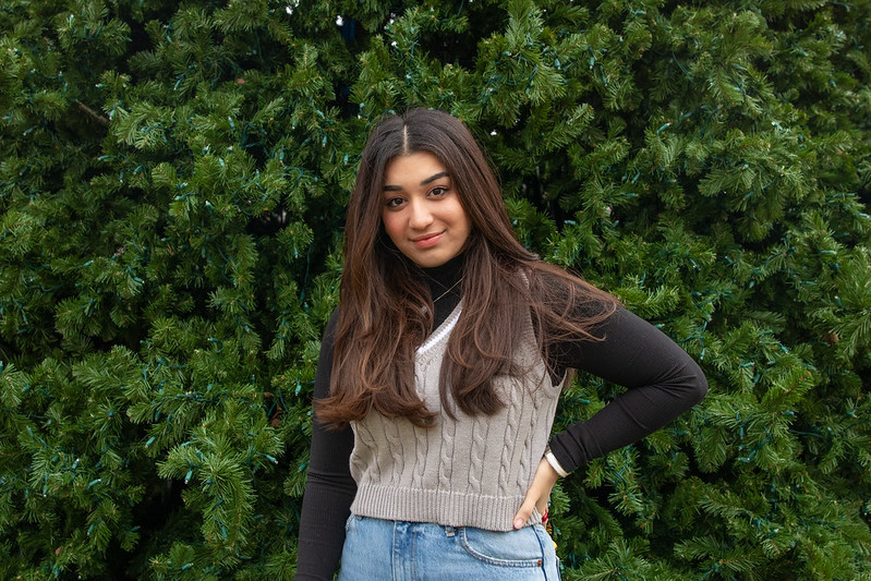 Rowan University student Rohama stands in front of a green tree, hand on her hip.