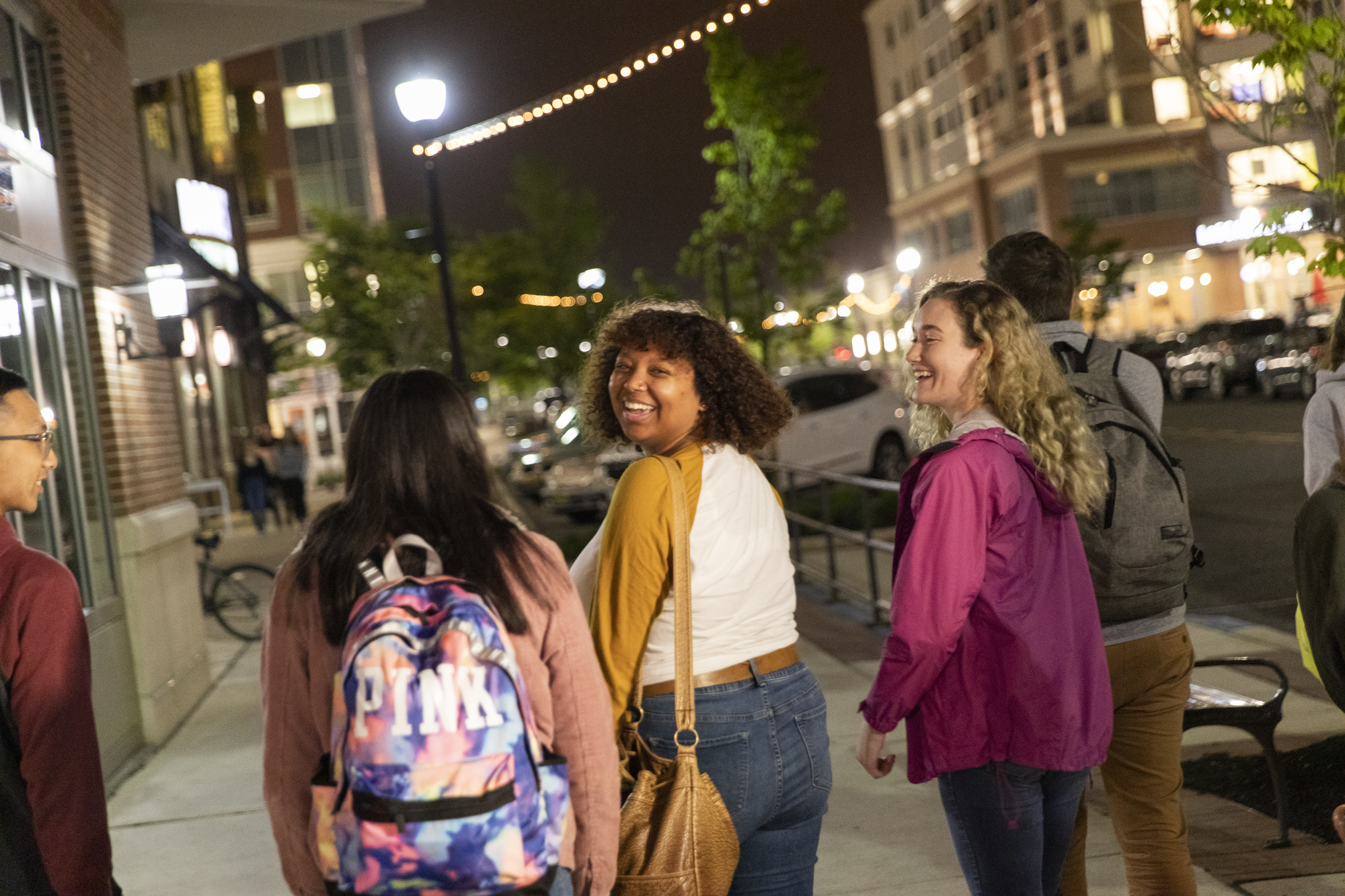 Girl smiles over her shoulder on Rowan Boulevard at night. 