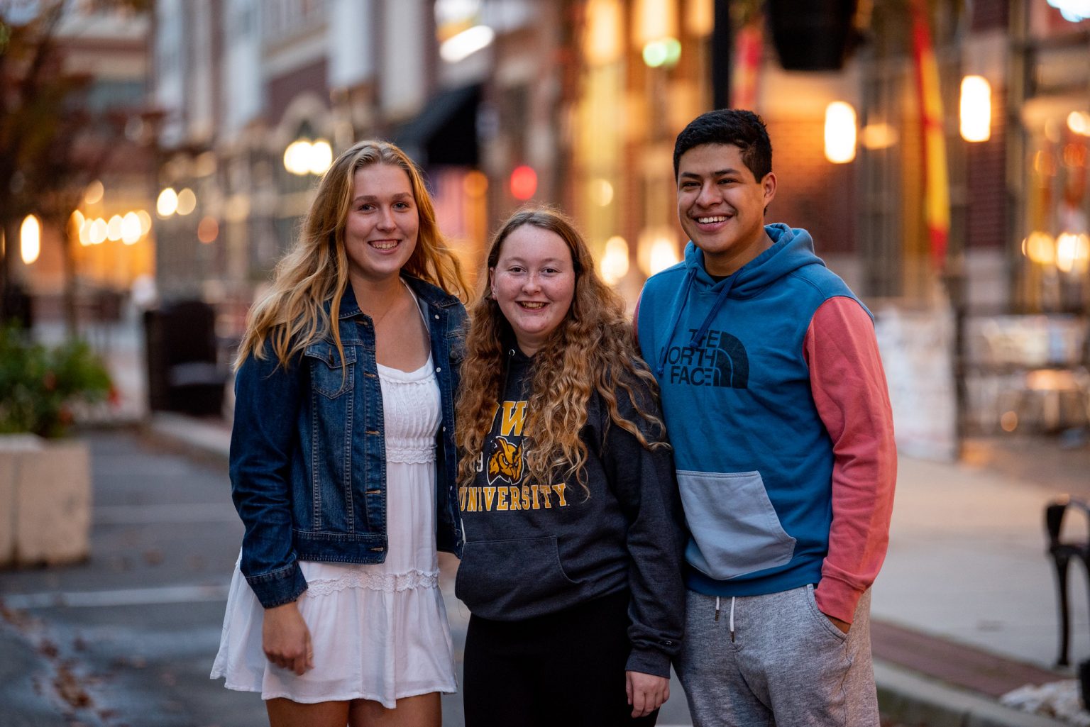 Three students, Taylor in the middle, posing on Rowan Boulevard.